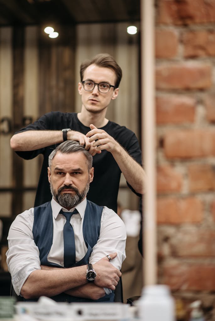 A skilled barber styling a man's hair in a professional barbershop setting.