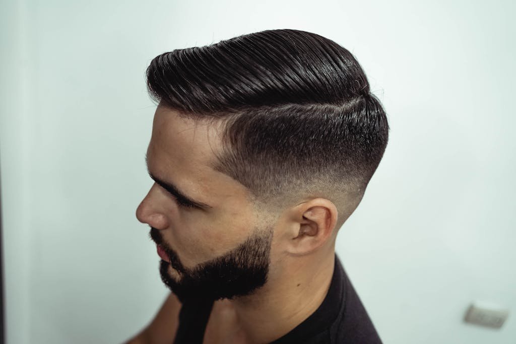 Close-up shot of a man's stylish haircut and beard, showcasing grooming precision.